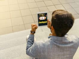 How to Increase Your Chances of Hitting the Jackpot in Online Casinos Back view man getting jackpot on mobile app on tablet, playing slots online