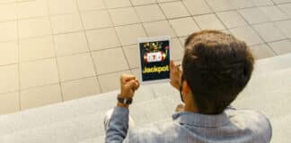 How to Increase Your Chances of Hitting the Jackpot in Online Casinos Back view man getting jackpot on mobile app on tablet, playing slots online