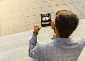 How to Increase Your Chances of Hitting the Jackpot in Online Casinos Back view man getting jackpot on mobile app on tablet, playing slots online