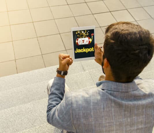 How to Increase Your Chances of Hitting the Jackpot in Online Casinos Back view man getting jackpot on mobile app on tablet, playing slots online